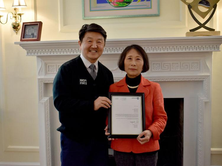 Penn State DuBois chancellor and chief academic officer Jungwoo Ryoo, right, presents Pingjuan Werner with a framed copy of the letter certifying her as a distinguished professor, the highest professorial distinction at the University